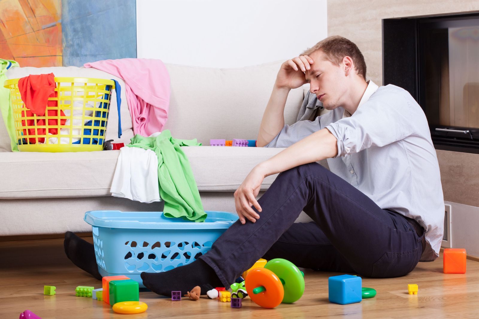 Father sitting with child nearby looking thoughtful and tired in a calm home