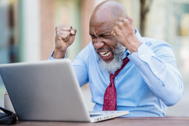 African American businessman showing frustration working on a laptop outdoors.