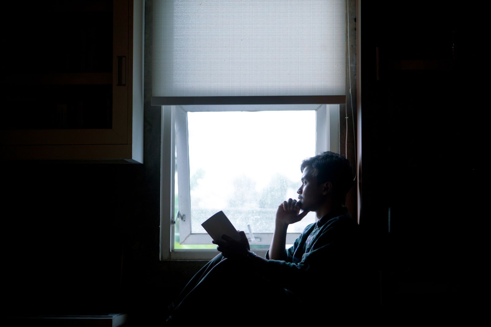 Adult sitting beside a sunlit window with autumn trees outside